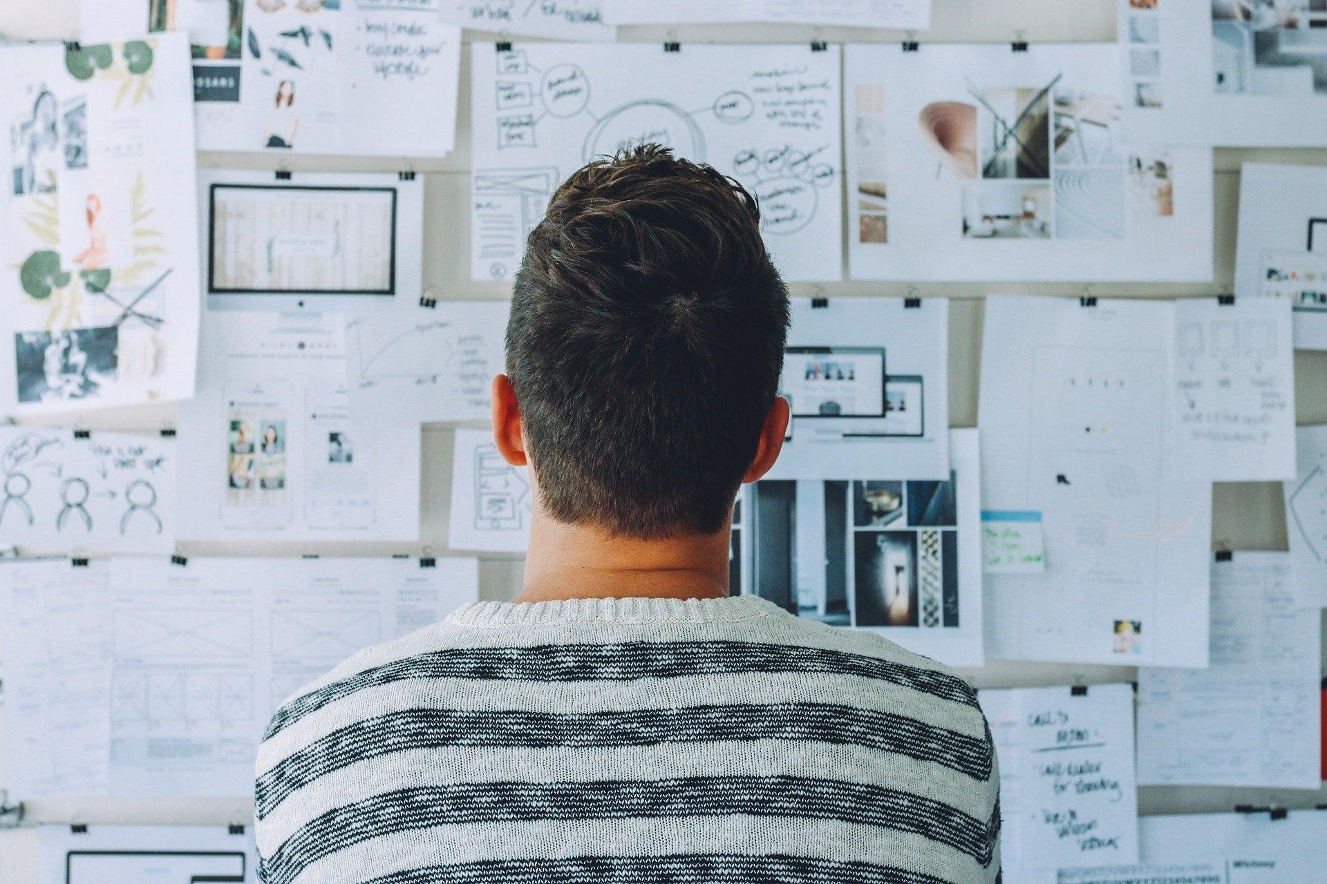 Das Bild zeigt einen Mann vor einem Whiteboard, das bedeckt ist von Skizzen und Plänen. Es steht als Symbol für die Konzeptionsphase Ihrer eigenen Website.